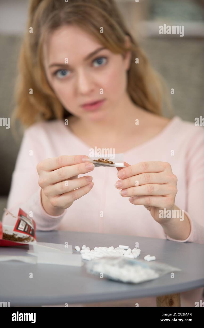 Porträt eines heranwachsenden Mädchens, das eine Zigarette rollt Stockfoto