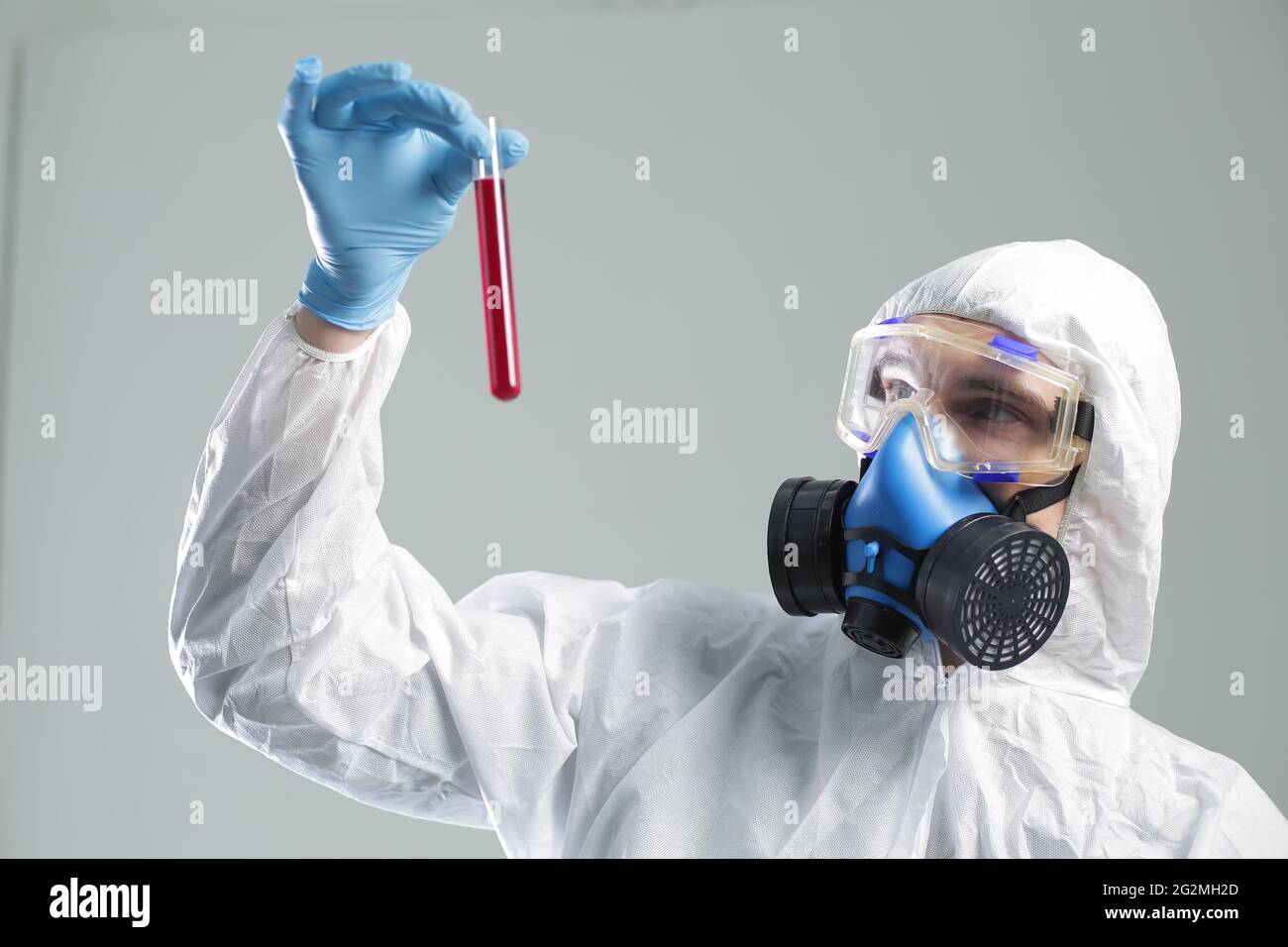 Ein Mann im Schutzanzug hält ein Reagenzglas in den Händen. Das Konzept der offenen Impfstoffe gegen Coronavirus Stockfoto