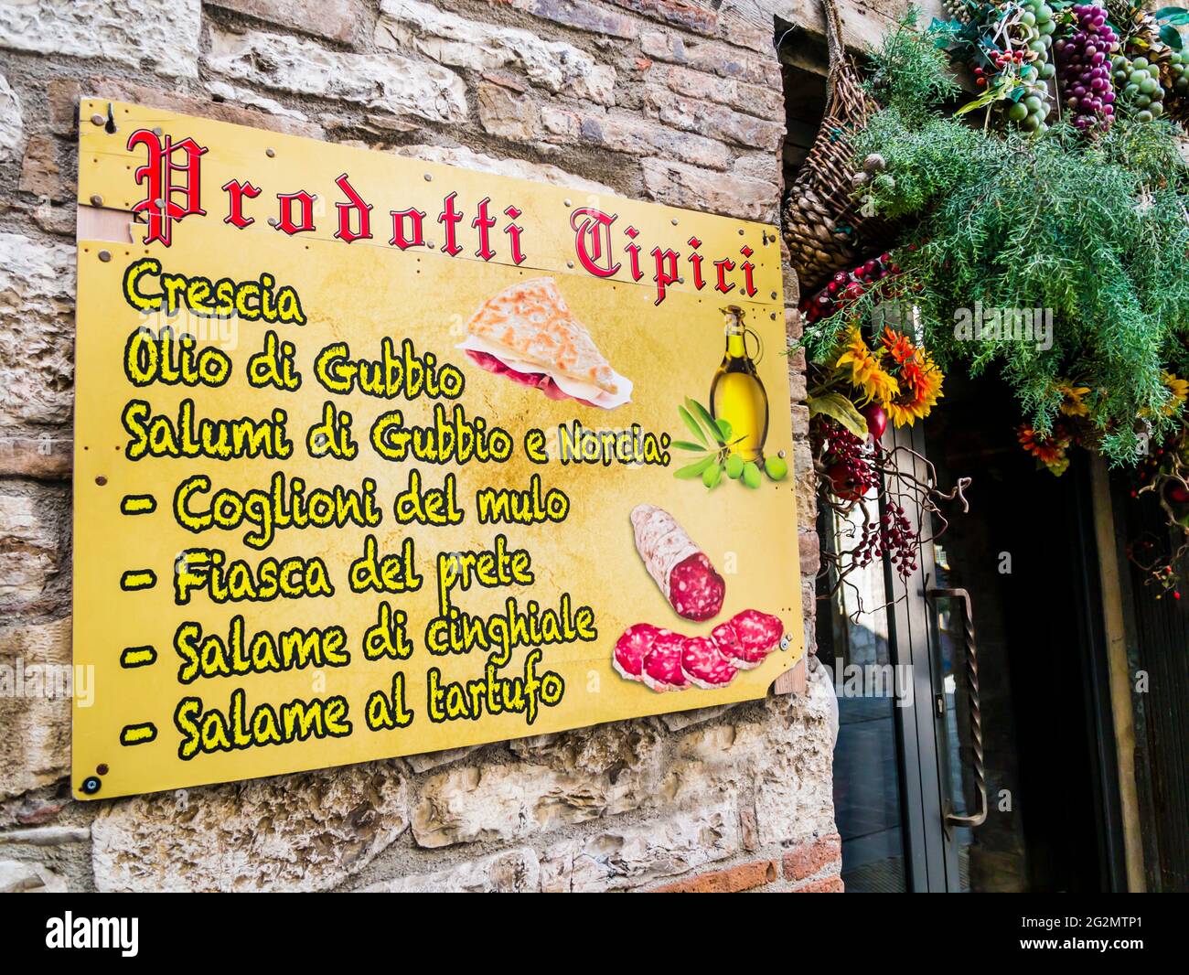 Buntes Straßenschild mit traditionellen Wurst-, Wein- und Olivenöl-Speisen, mittelalterliches italienisches Dorf Stockfoto