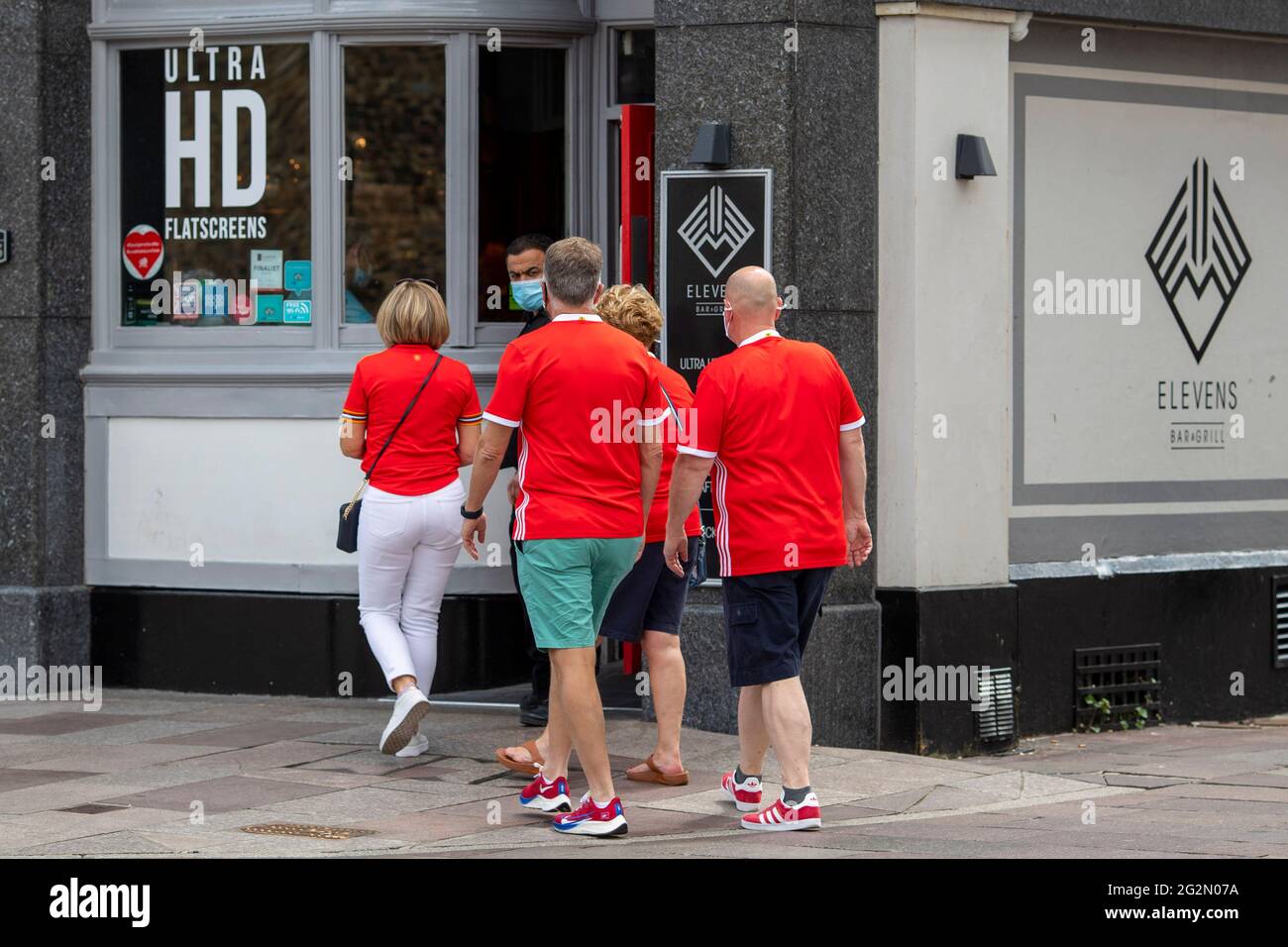 Cardiff, Wales, Großbritannien. Juni 2021. Fußballfans aus Wales betreten vor dem Eröffnungsspiel des Coronavirus, das das EM 2020-Turnier gegen die Schweiz in Aserbaidschan verzögert, eine Kneipe im Stadtzentrum von Cardiff. Kredit: Mark Hawkins/Alamy Live Nachrichten Stockfoto