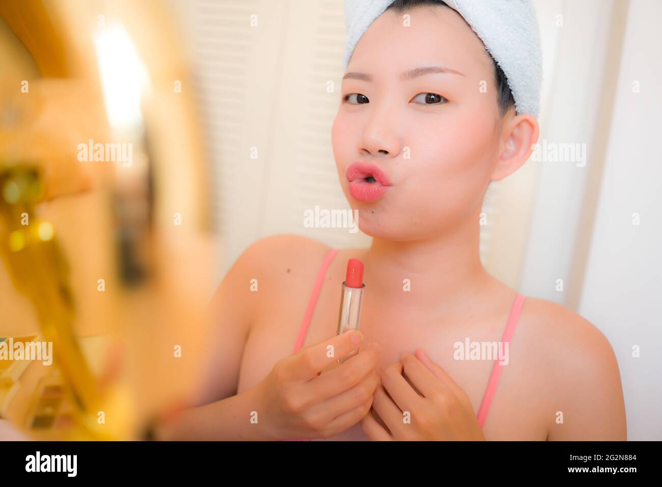 Junge asiatische Frau, die Make-up - schöne und attraktive chinesische Mädchen mit Kopftuch setzen Gesichts Make-up zu Hause am Morgen in Schönheit und Stockfoto