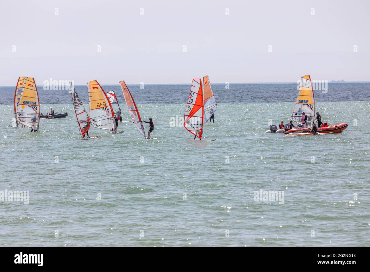 Eine Gruppe von Windsurfern, die sich für einen Wettkampf auf einem ruhigen Meer vorbereiten. Stockfoto