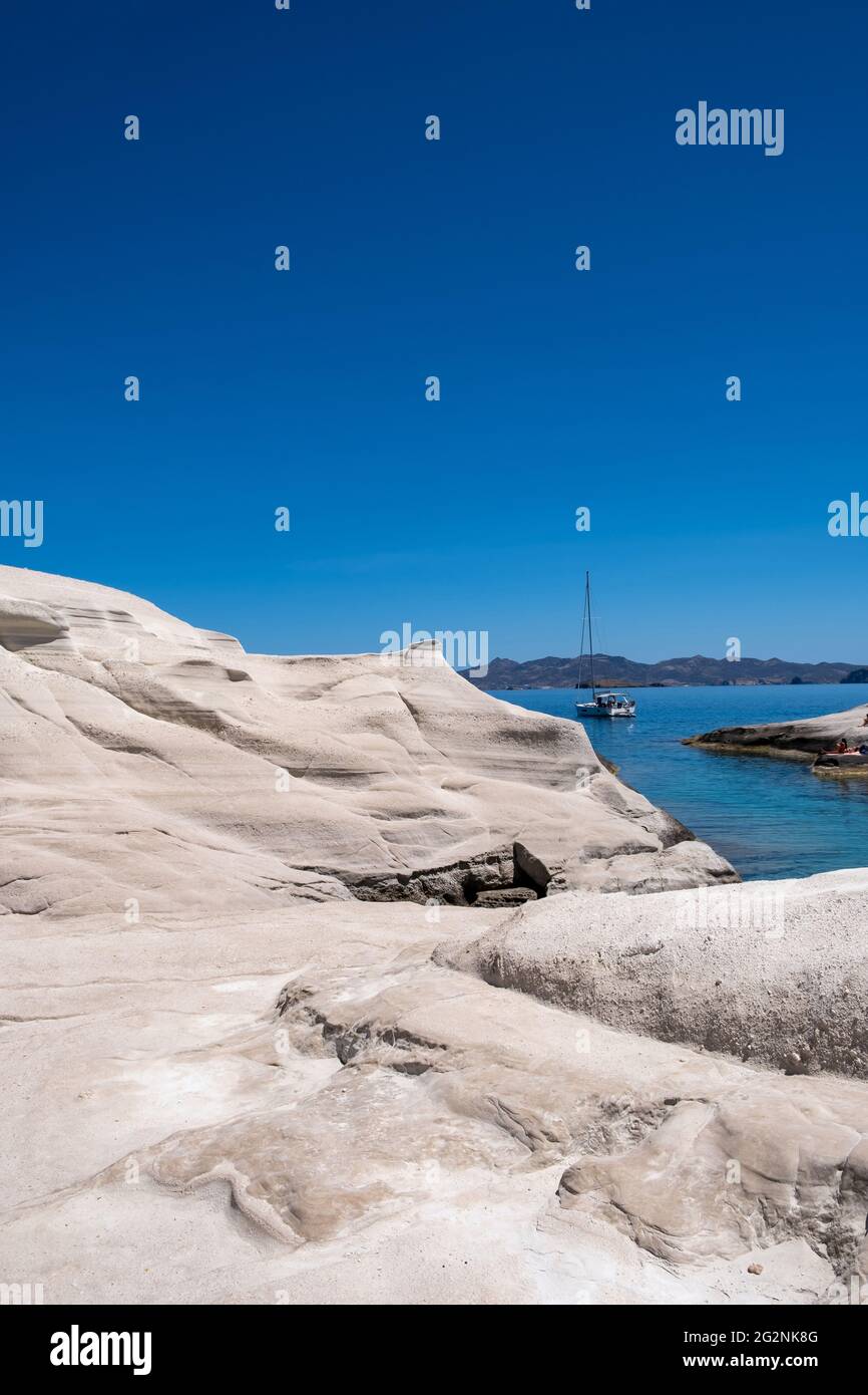 Insel Milos, Sarakiniko. Kykladen Griechenland. Mondlandschaft, weiße Felsformationen, Klippen und Höhlen, blaues, gewelltes Meer und klarer Himmel im Hintergrund. Stockfoto