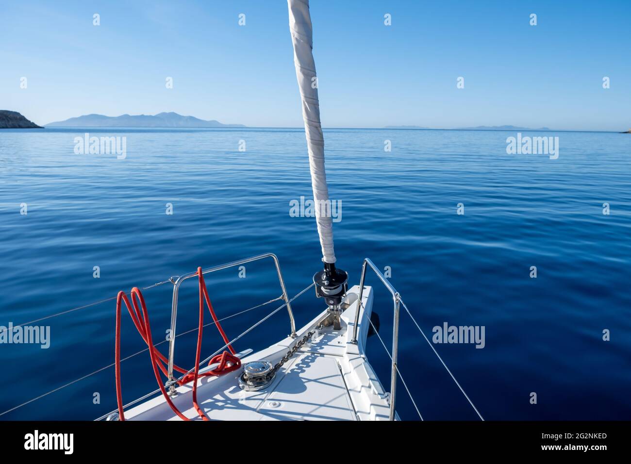 Weißes Segelboot vor Deck Teil in ruhigen Ozean, kein Wind, blauer Himmel Hintergrund. Yacht auf Kreuzfahrt auf dem Ägäischen Meer. Raum, Sommerurlaub Karte, inserieren Vorlage Stockfoto