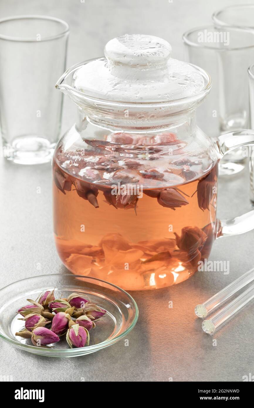 Teekannen aus Glas mit getrockneten Rosenblüten als aromatisches Heißgetränk Stockfoto