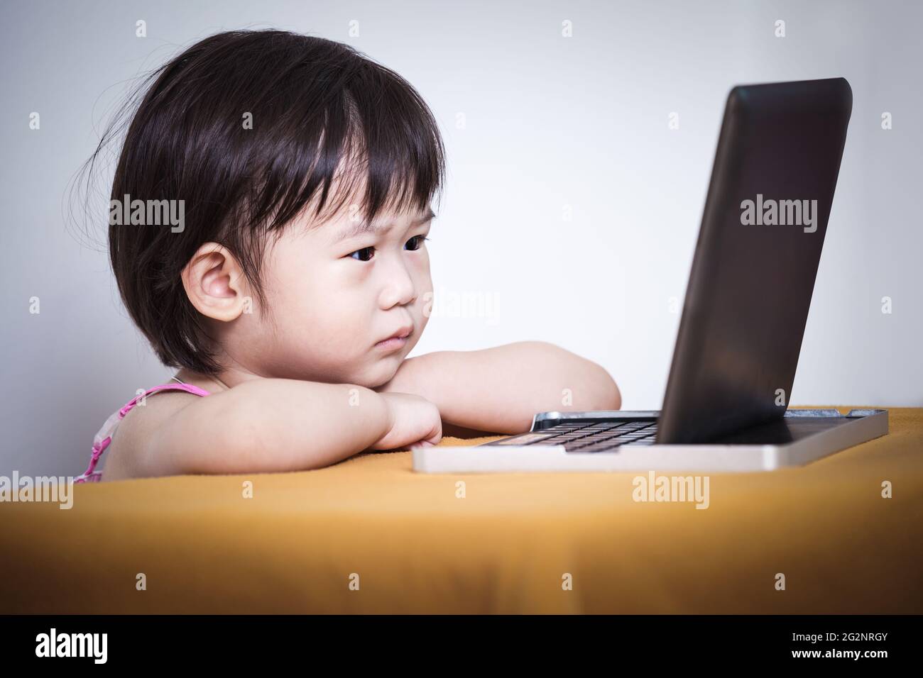 Ernsthaftes Kind, das auf einem digitalen Tablet-Computer mit Touchscreen sitzt und eine Geschichte anschaut, Konzept über Optik und Lernen, Studioaufnahme Stockfoto