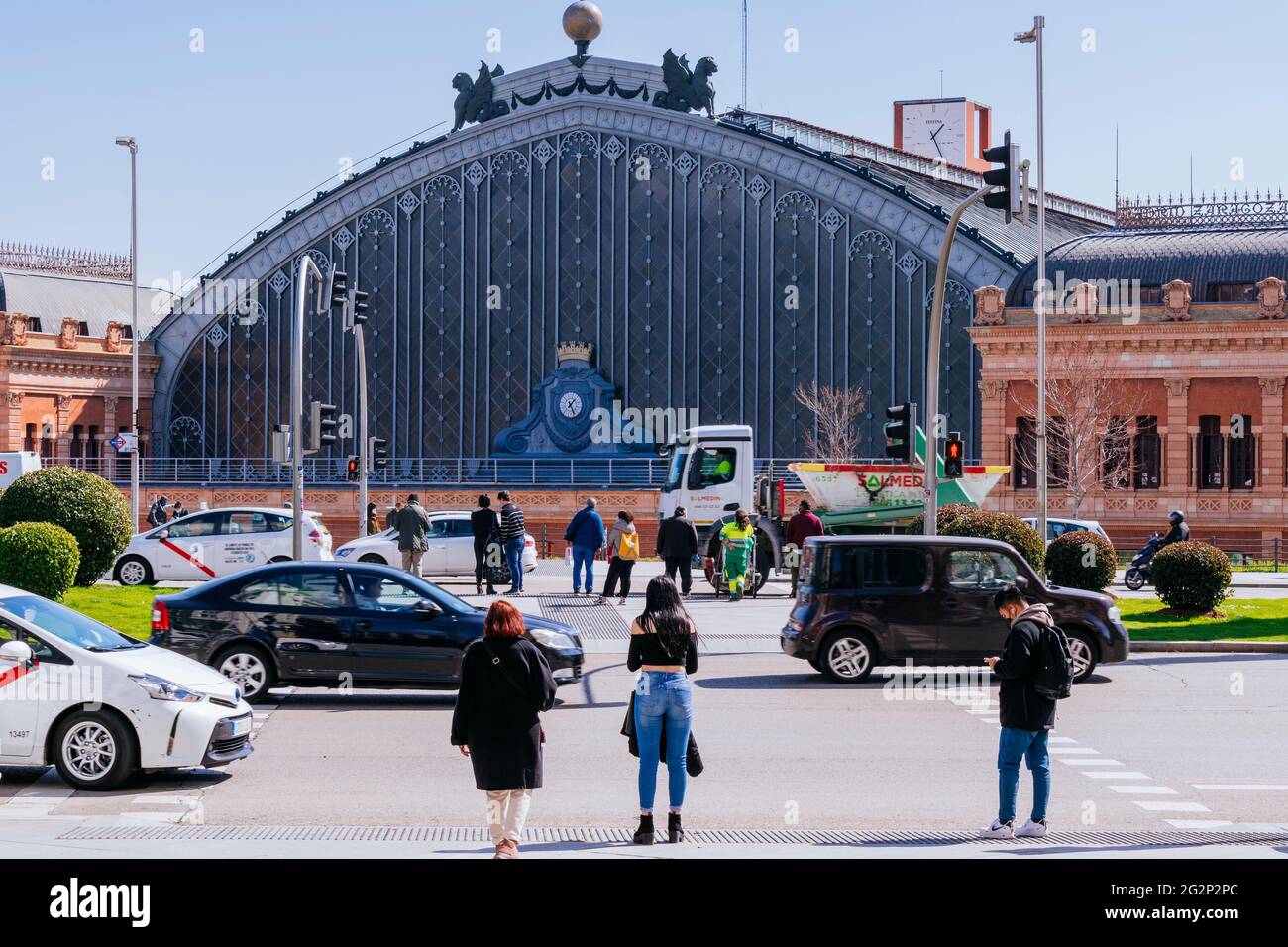 Fußgänger, die durch den Emperador Carlos V Platz gehen, im Hintergrund den Bahnhof Atocha. Madrid, Comunidad de Madrid, Spanien, Europa Stockfoto