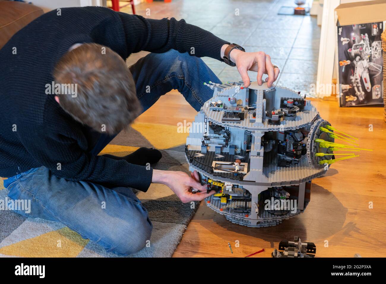 Ein Mann in den 30er Jahren, der in seinem Wohnzimmer zu Hause ein Lego-Modell des Star Wars-Todessterns baute. VEREINIGTES KÖNIGREICH. Thema: Hobbys für Erwachsene, Sperrzeiten Stockfoto