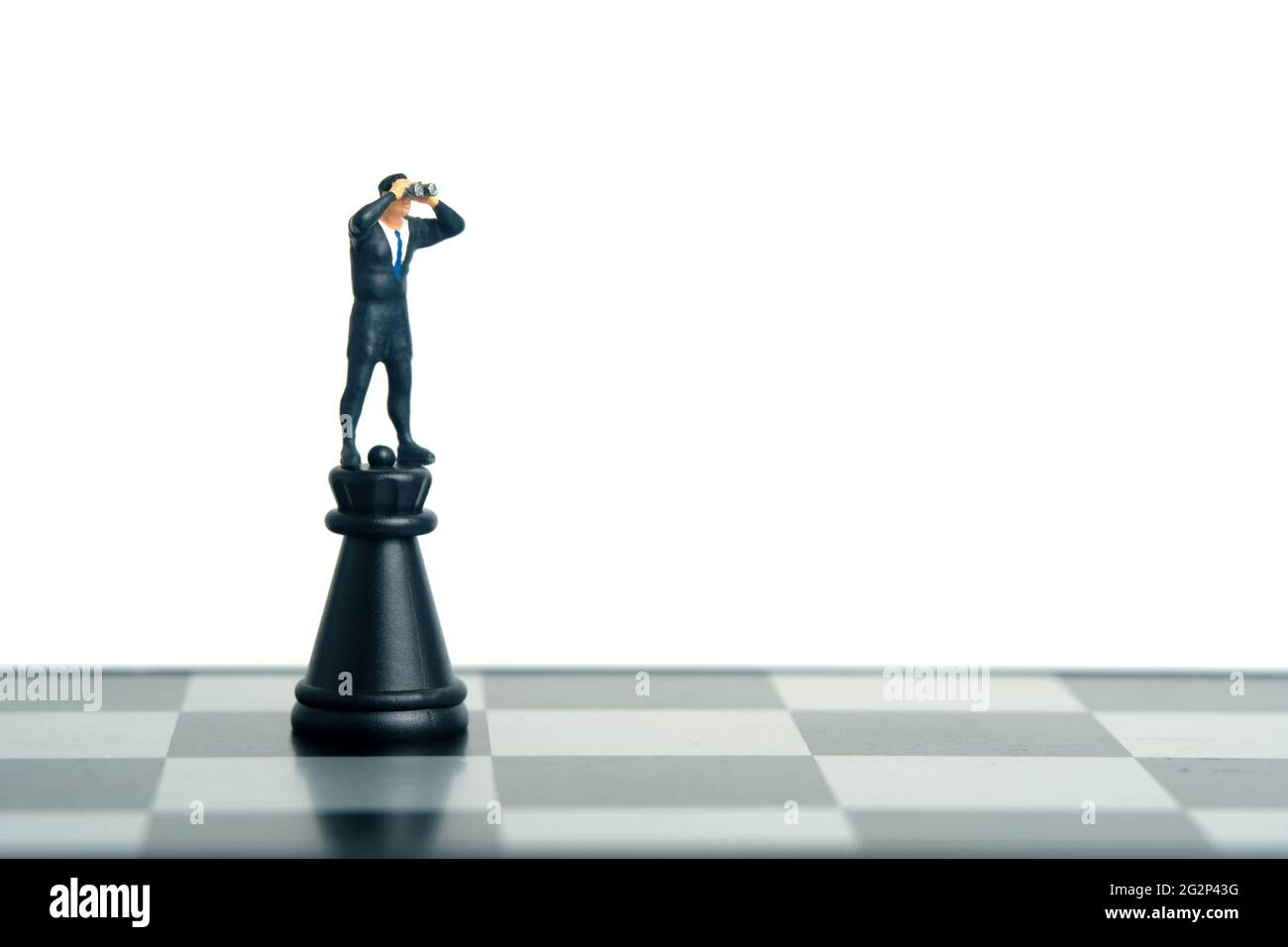 Geschäftsmann mit Ferngläsern, die über der Burg der Festung stehen. Miniatur winzigen Menschen Spielzeug Fotografie. Isoliert auf weißem Hintergrund Stockfoto