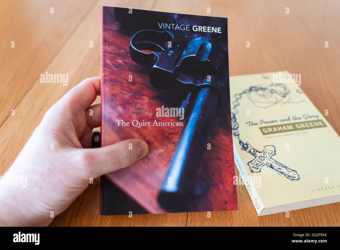 Ein Mann hält den Roman der ruhige Amerikaner des englischen Autors Graham Greene Stockfoto
