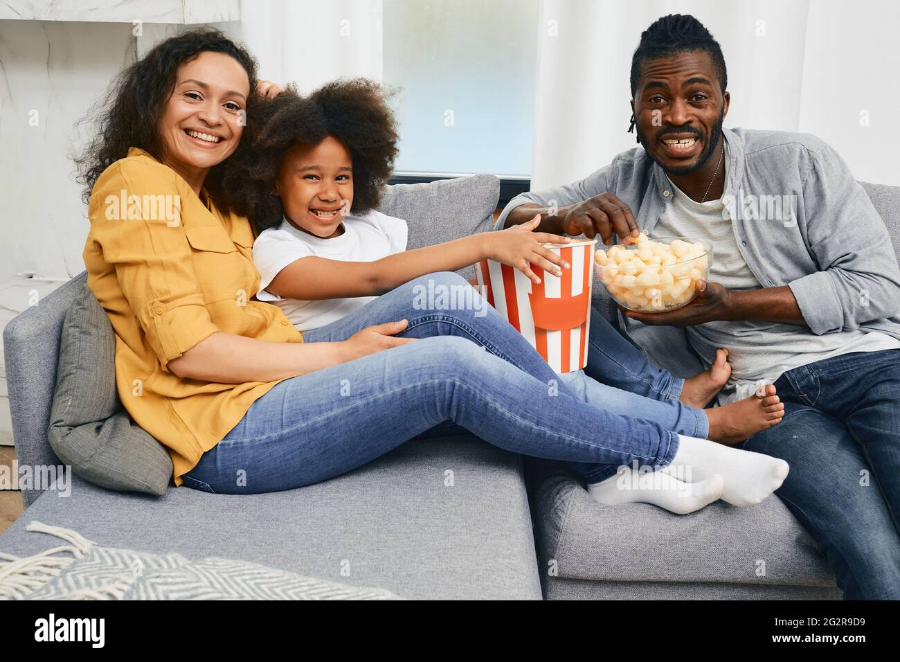Glückliche afroamerikanische Familie genießt, einen Film in ihrem Haus auf Fernsehapparat zu sehen Stockfoto