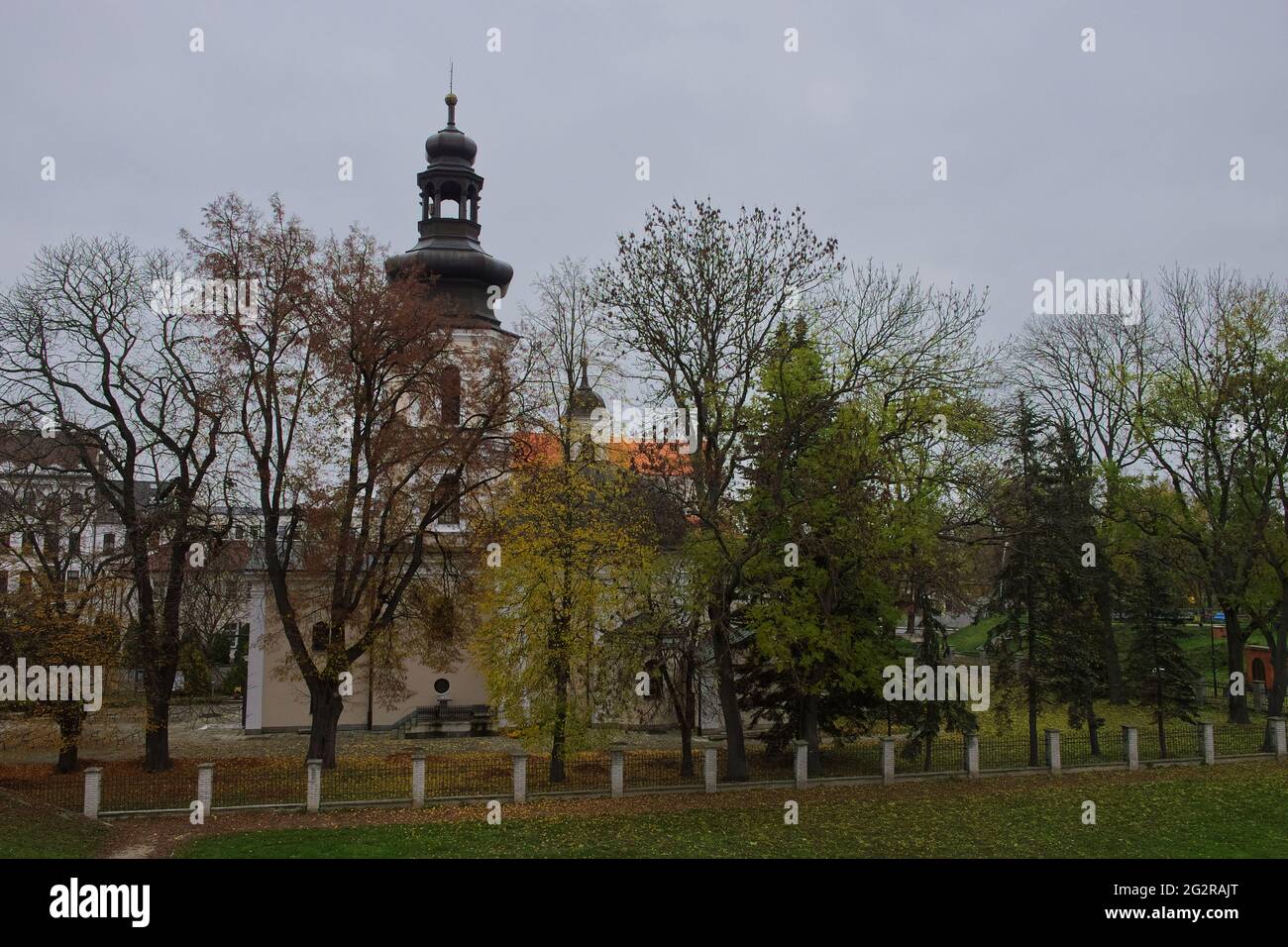 Römisch-katholische Kirche St. Nikolaus, Zamosc. Alte katholische Kirche umgeben von Herbstbäumen, Landschaft. Stockfoto
