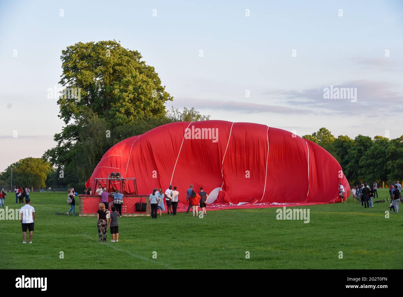 12. Juni 2021 - Northampton - UK = Virgin Hotair Ballon Rides landet auf dem Rennbahnpark, während die Menge zuschaut, wie es entflat Stockfoto