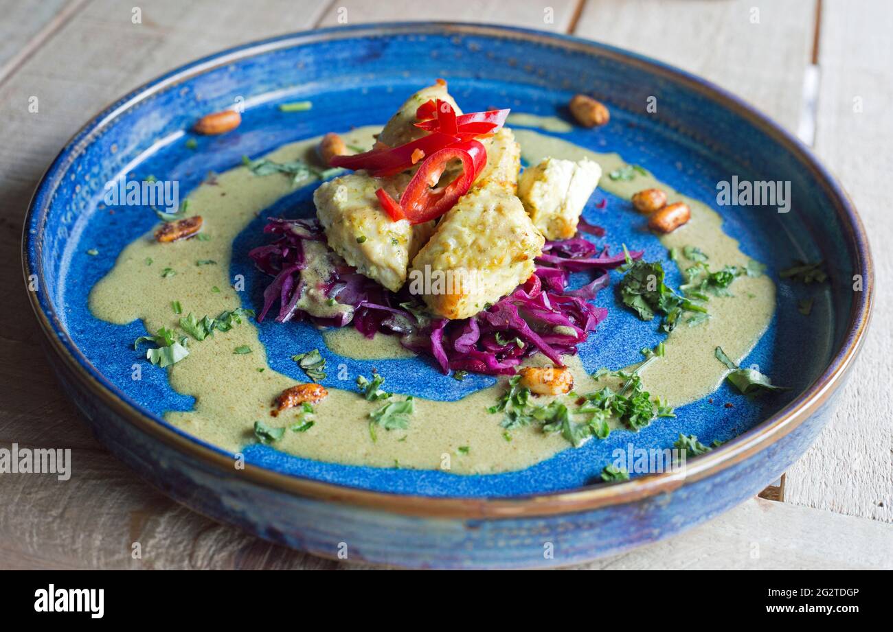 Hähnchen Satay präsentiert auf einem blauen Teller und fotografiert aus der Nähe unter natürlichem Licht. Stockfoto
