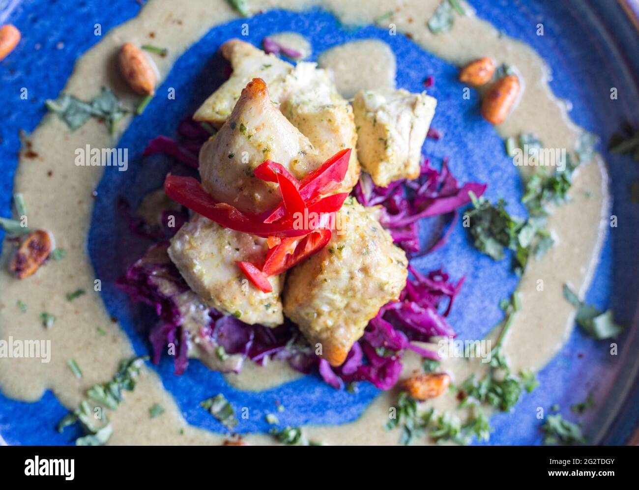 Hähnchen Satay präsentiert auf einem blauen Teller und fotografiert aus der Nähe unter natürlichem Licht. Stockfoto