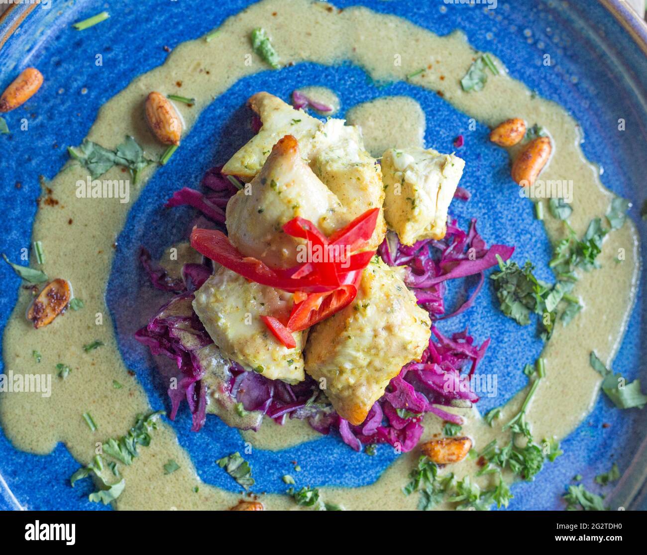 Hähnchen Satay präsentiert auf einem blauen Teller und fotografiert aus der Nähe unter natürlichem Licht. Stockfoto