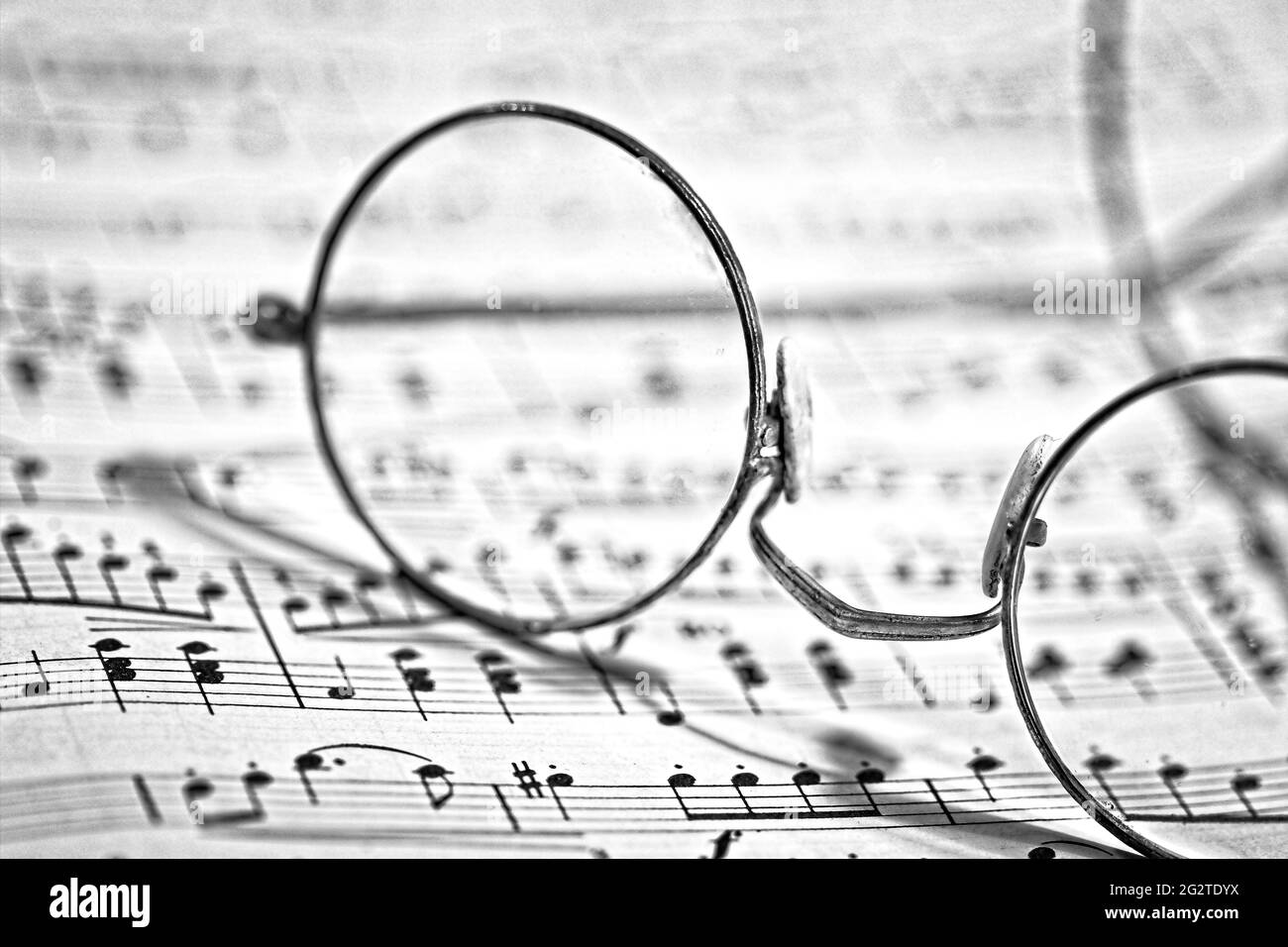 Schwarz-Weiß-Bild mit alten Brillen auf Noten. Geeignet für Musikzentren, Büros oder Hotel-/Motel-Lobbys, Flure und Zimmer, Stockfoto