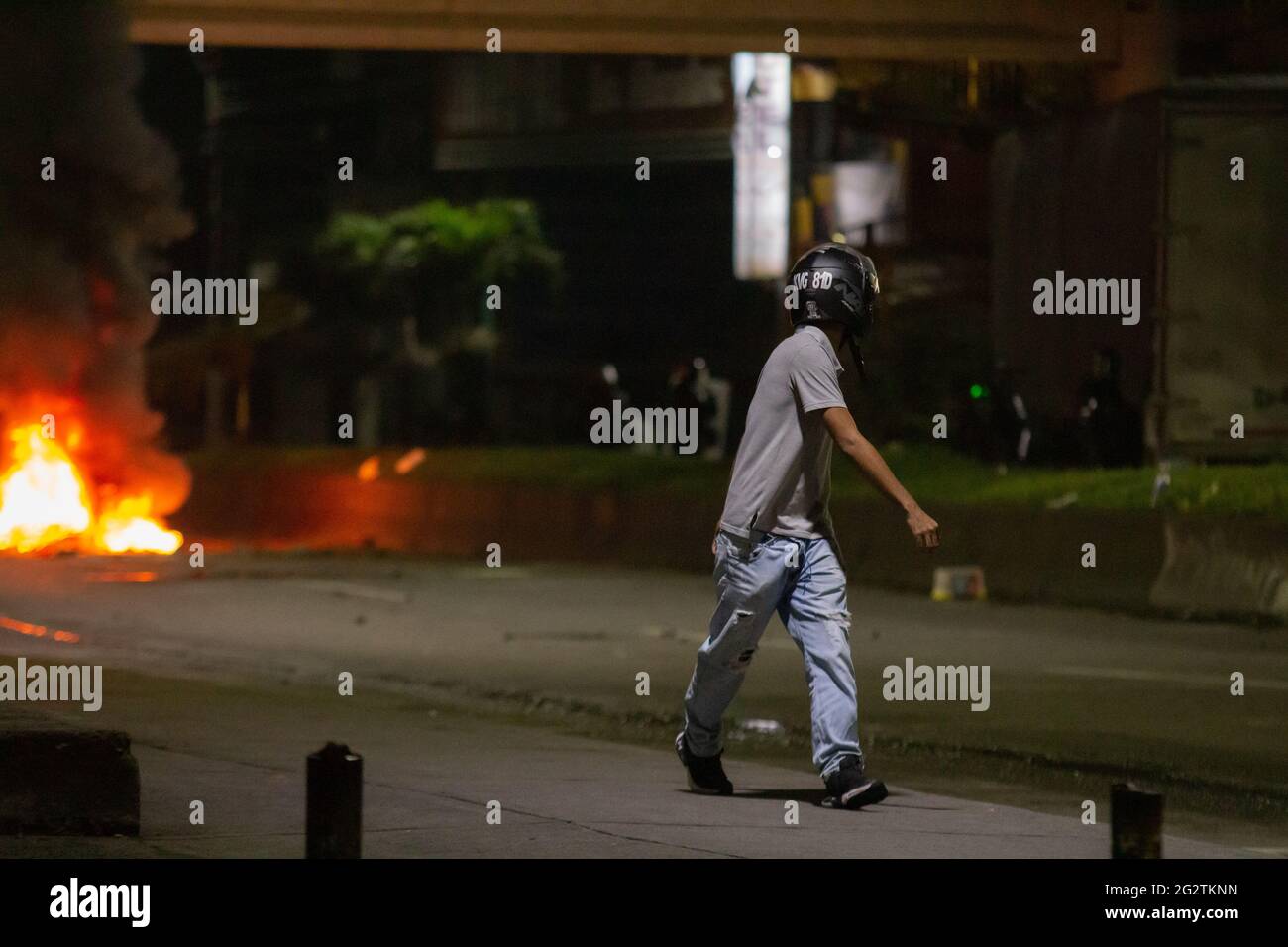 Ein Demonstranten, der einen Helm verwendet, nimmt an einem regierungsfeindlichen Protest Teil, während Menschen auf der Straße, die Cartago, Valle del Cauca mit der Stadt Pereira, Risaralda, Kolumbien, verbindet, mit der kolumbianischen Bereitschaftspolizei (ESMAD) zusammenstoßen. 11. Juni 2021. Stockfoto Ein Demonstranten, der einen Helm verwendet, nimmt an einem regierungsfeindlichen Protest Teil, während Menschen auf der Straße, die Cartago, Valle del Cauca mit der Stadt Pereira, Risaralda, Kolumbien, verbindet, mit der kolumbianischen Bereitschaftspolizei (ESMAD) zusammenstoßen. 11. Juni 2021. Stockfoto