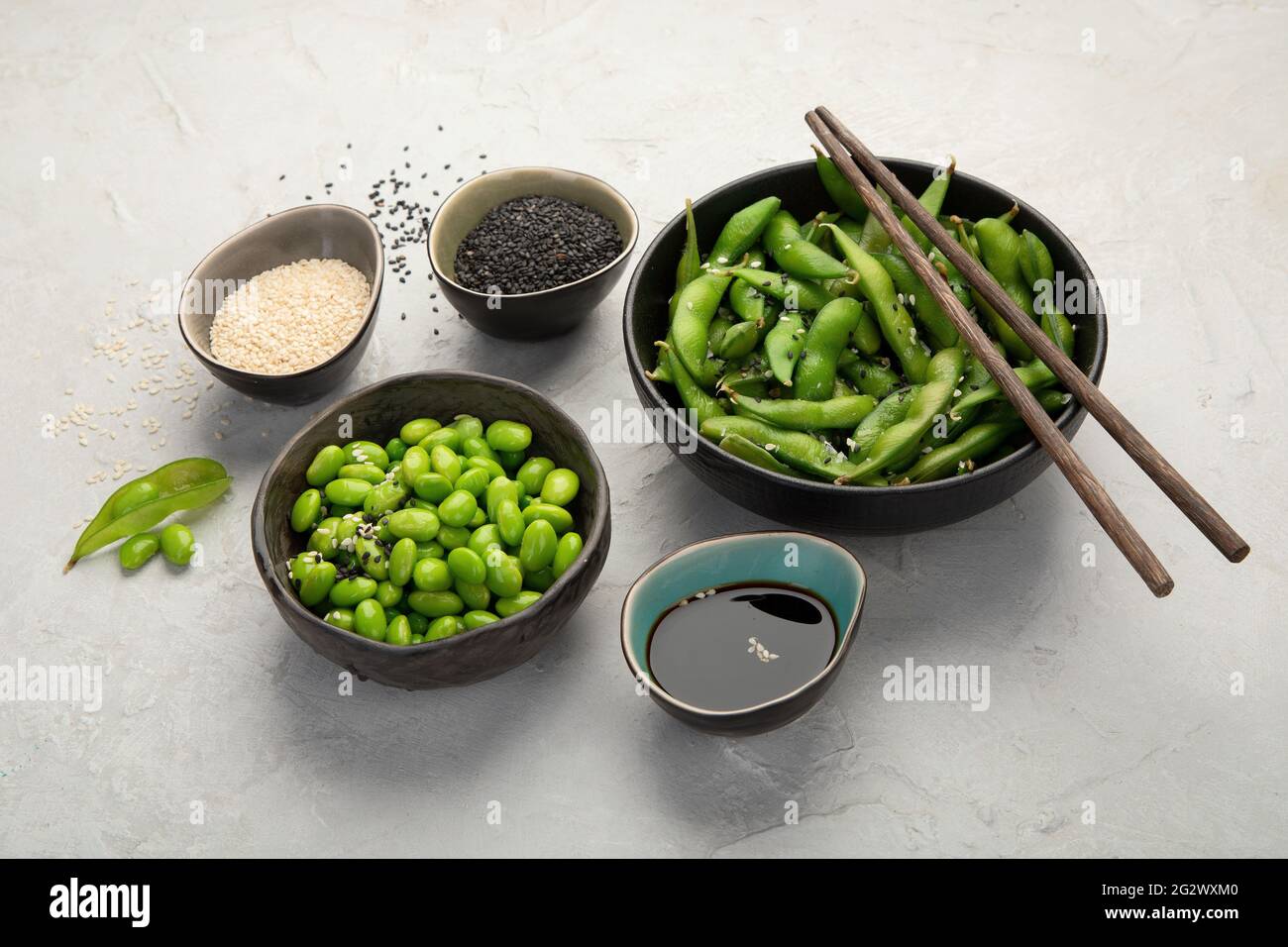 Rohe Sojabohnen mit Edamame und Salz und Sauce auf hellgrauem Hintergrund. Stockfoto