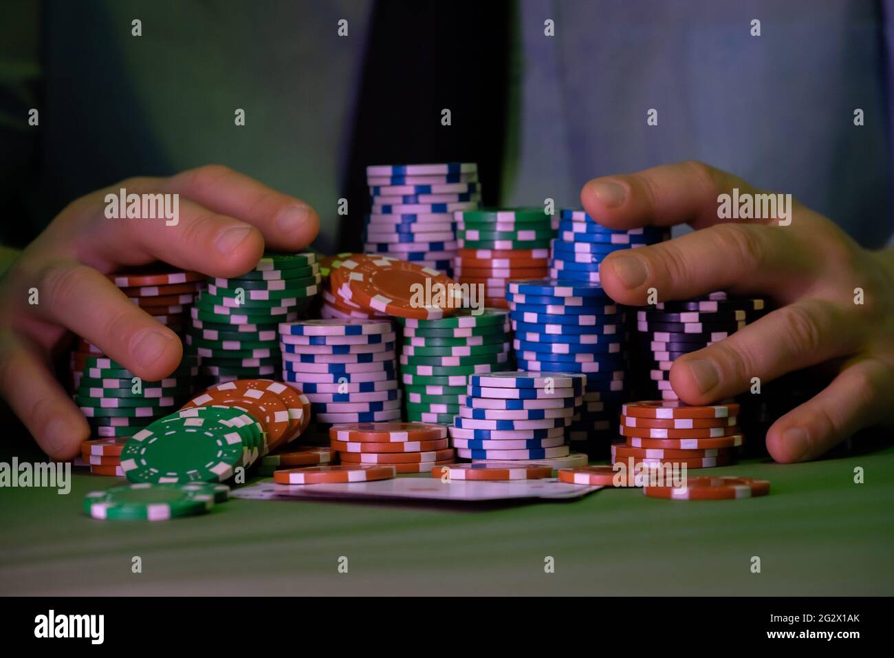 Der Mann spielt im Casino. Nur Chips und Hände sind über dem Tisch sichtbar. Der Hintergrund ist sehr unscharf. Stockfoto