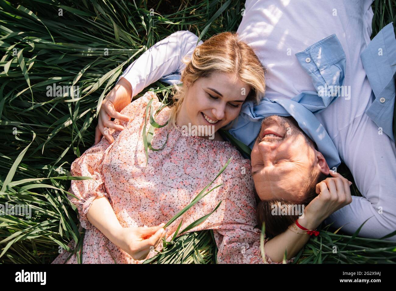 Glückliches junges Paar, das zusammen im Park auf Gras träumt, freuen sich junge Bauern darüber Stockfoto