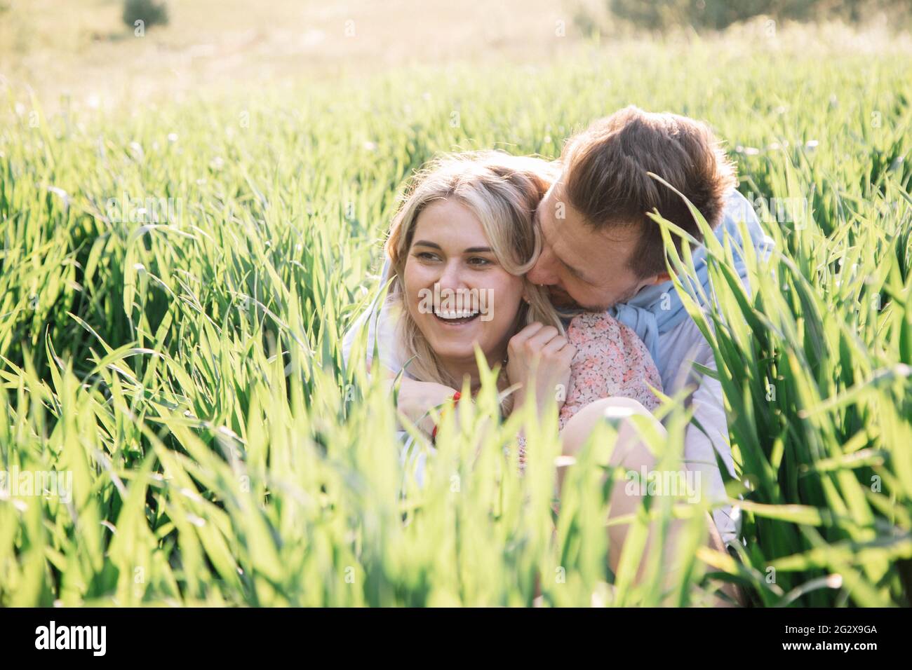 Glückliches junges Paar, das träumt und gemeinsam auf dem Rasen auf Gras Spaß hat, freuen sich junge Bauern über die Ernte Stockfoto