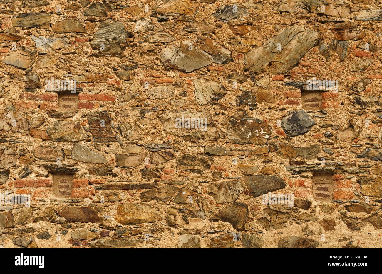 Alte Außenwand einer Kirche mit Stein und Ziegel in warmen Tönen und viel Textur. Stockfoto Alte Außenwand einer Kirche mit Stein und Ziegel in warmen Tönen und viel Textur. Stockfoto