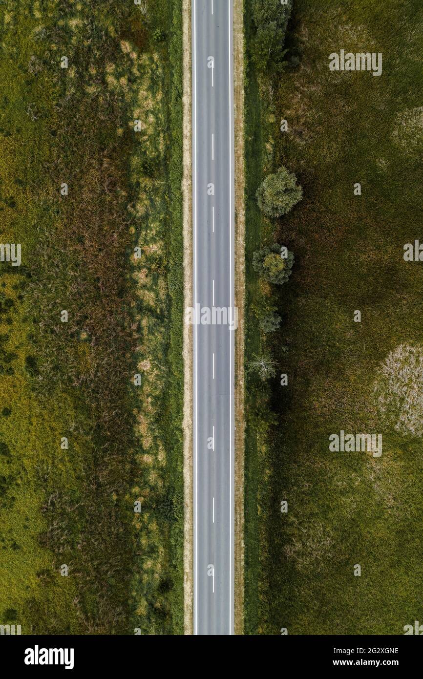 Leere Asphaltstraße durch die Landschaft, Luftaufnahme von Drohne pov, Draufsicht Fahrbahn als konzeptioneller Hintergrund für Reise- und Autoversicherungsthemen. Stockfoto