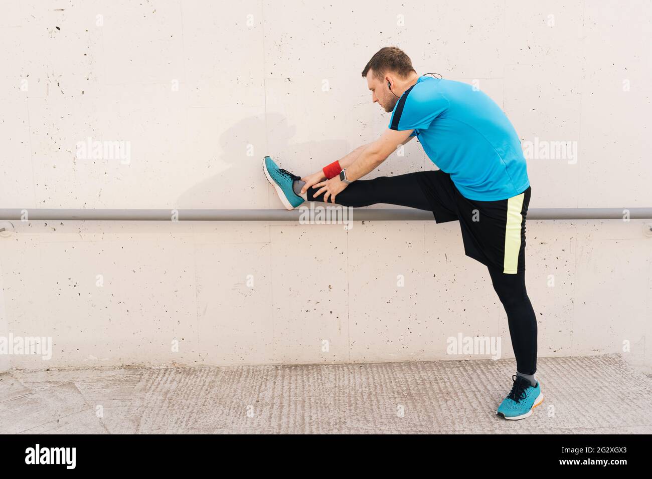 Junger Mann Läufer immer bereit zu laufen Stretching Beine wärmen Quad Stretch Übung auf Außentreppe Stockfoto