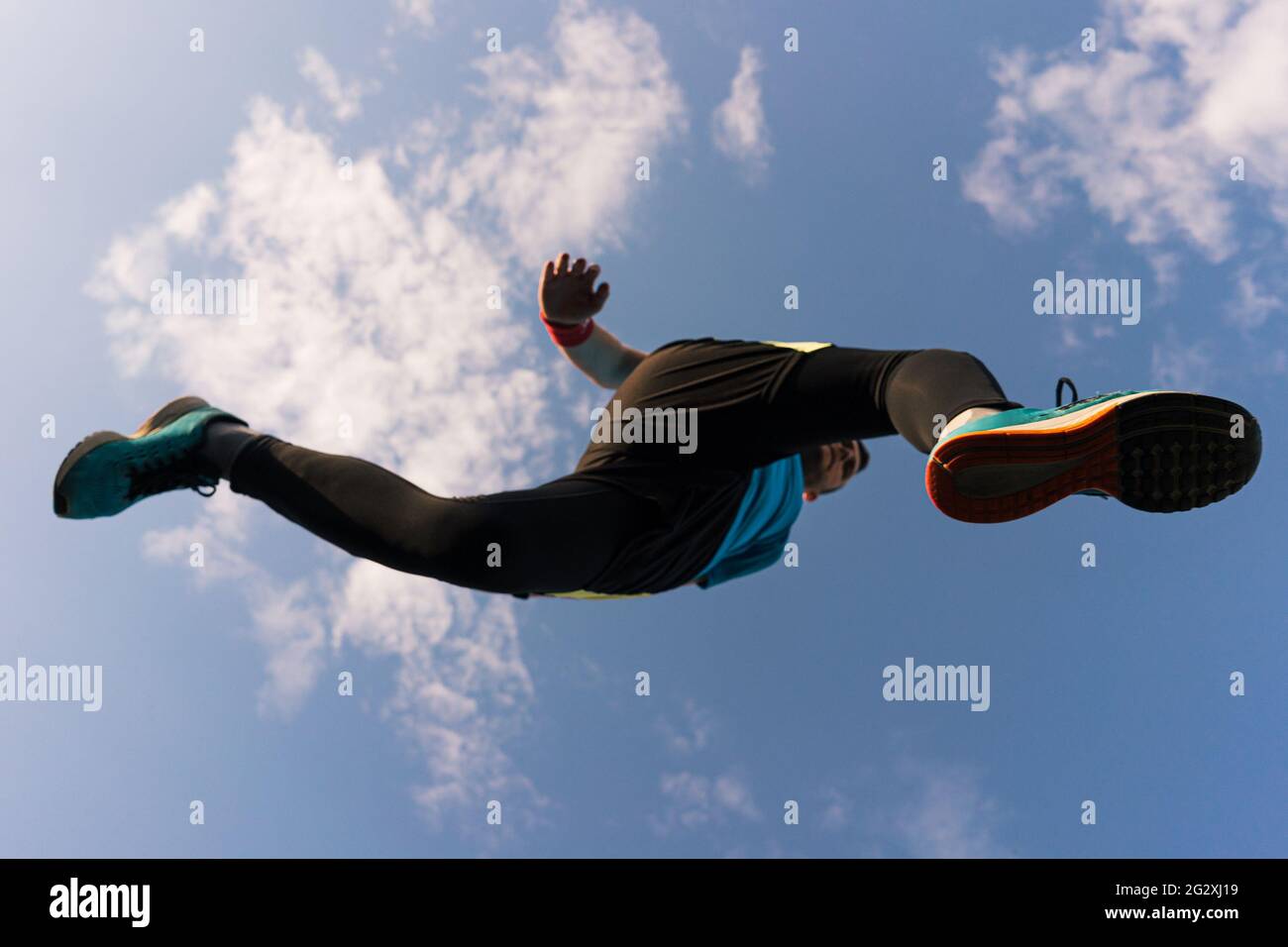 Low-Angle-Ansicht eines Sportlers, der springt und läuft mit blauem Himmel im Hintergrund Stockfoto