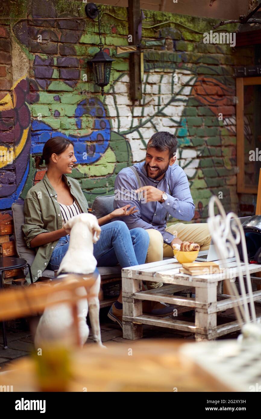 Junges Paar mit einer guten Zeit im Café im Freien mit ihrem Hund sitzen. Copy Space, selektive Fokus Bild. Stockfoto
