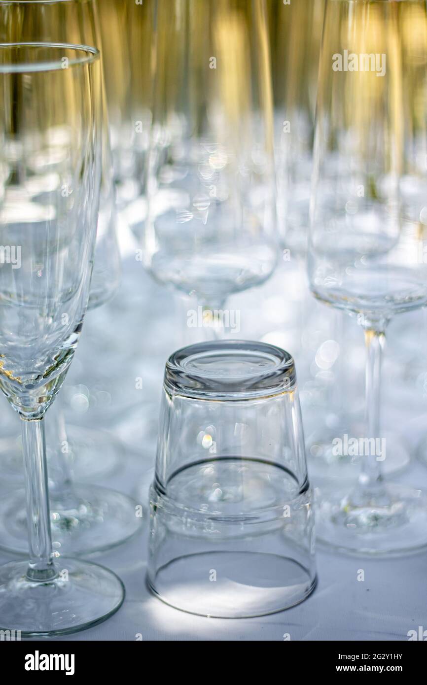 Nahaufnahme verschiedener Gläser, Sektgläser und Cocktailgläser auf einem Tisch mit weißer Tischdecke, Fokus auf Cocktailglas Stockfoto
