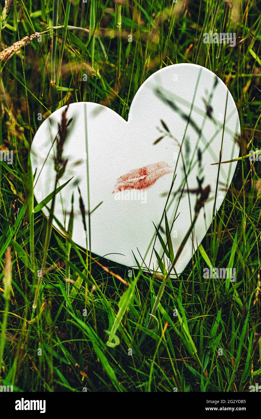 Weißes Liebesherz mit einem roten Lippenstift-Kuss Stockfoto