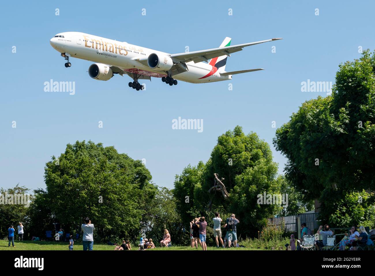 Flughafen London Heathrow, London, Großbritannien. Juni 2021. Luftfahrtbegeisterte versammeln sich an beliebten Orten in Heathrow, um die Boeing VC-25A (umgebauter Jumbo Jet aus dem Jahr 747) der „Air Force One“ zu fotografieren, die den US-Präsidenten Joe Biden vom G7-Gipfel in Newquay nach London transportiert. Normale Flugzeuge landen über ihnen. Das Wetter ist perfekt, mit klarem blauen Himmel. Emirates Boeing 777 im Finale Stockfoto