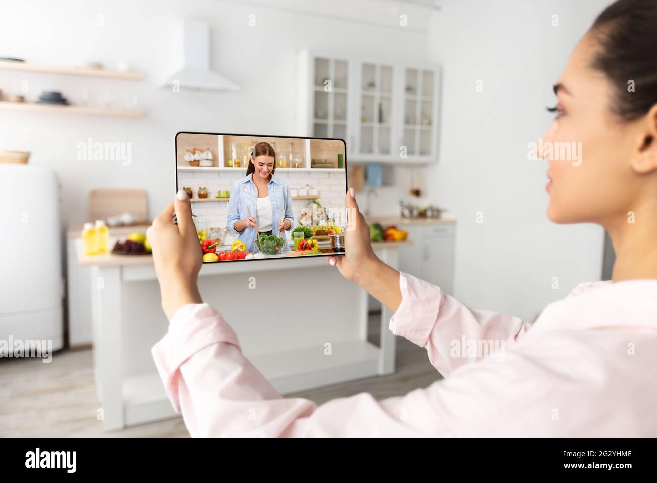 Junge Dame, die online kulinarische Tutorial in der Küche, mit Tablet-pc, Fernstudium während covid Lockdown Stockfoto