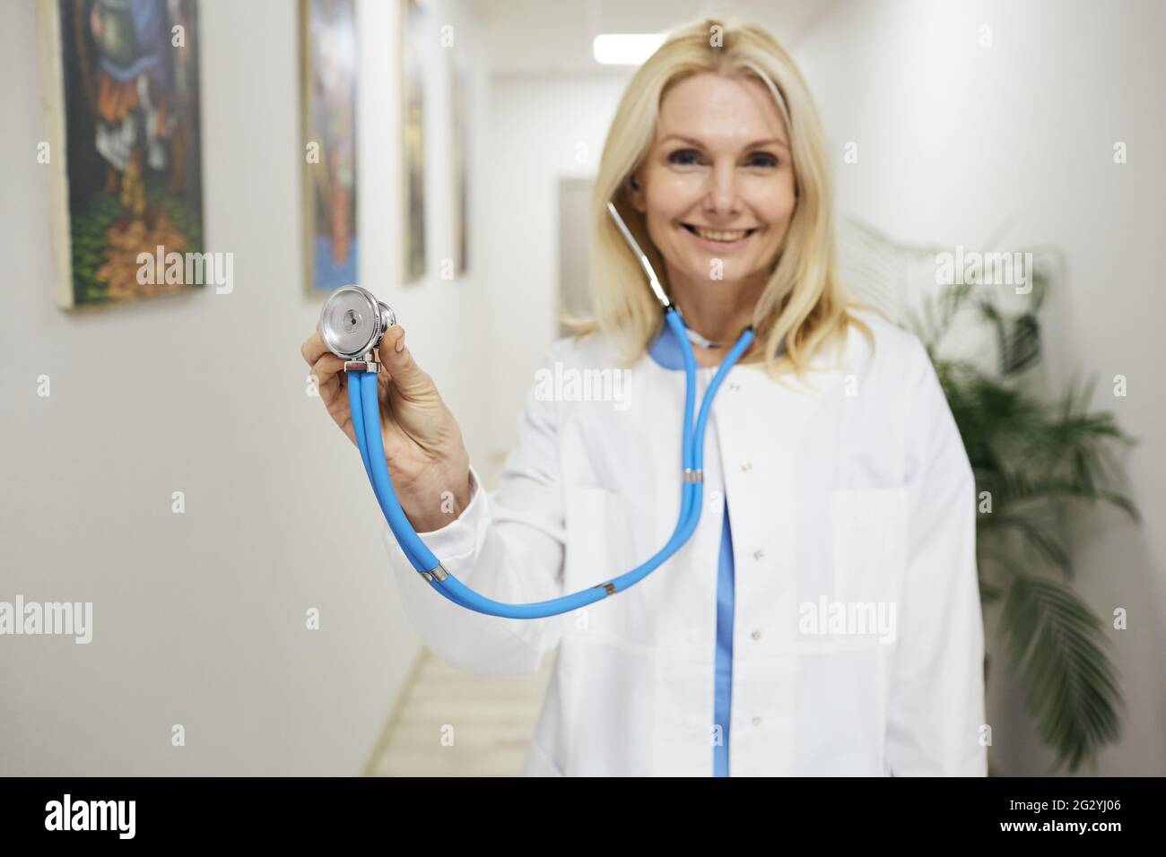 Arztberuf. Erfahrene Hausärztin mit medizinischem Mantel mit Stethoskop in der Hand, stehend in einer medizinischen Klinik, Porträt Stockfoto