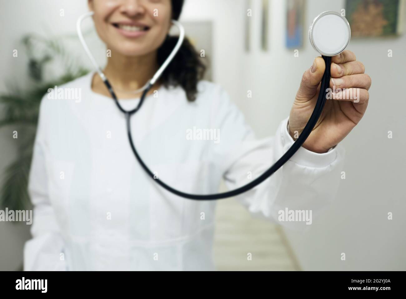 Arztberuf. Hausärztin mit medizinischem Mantel mit Stethoskop in der Hand, stehend in einer medizinischen Klinik, Porträt Stockfoto