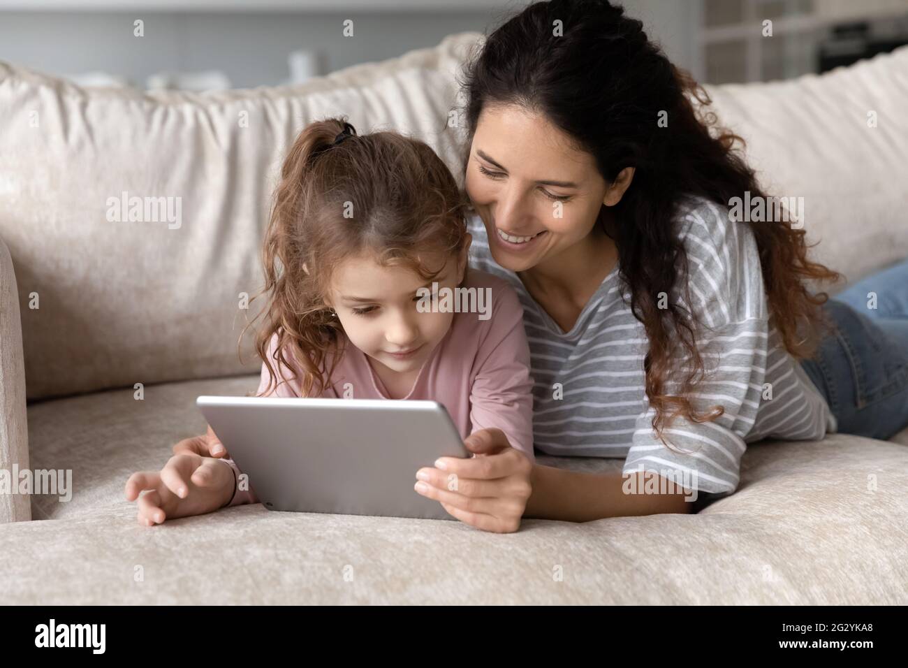 Lächelnde hispanische Mutter und Tochter verwenden Tablet zu Hause Stockfoto