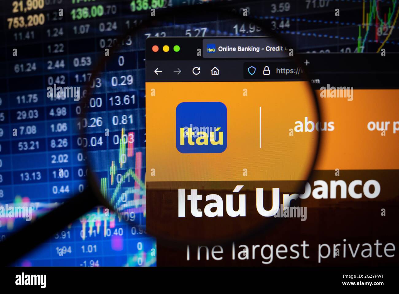 Firmenlogo der Banco Itau auf einer Website mit verschwommenen Börsenentwicklungen im Hintergrund, die auf einem Computerbildschirm durch eine Lupe gesehen werden Stockfoto