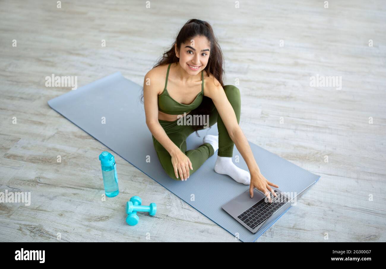 Junge indische Frau beobachten Online-Sport-Tutorial auf Laptop vor dem Training zu Hause. Aktiver Lebensstil Stockfoto