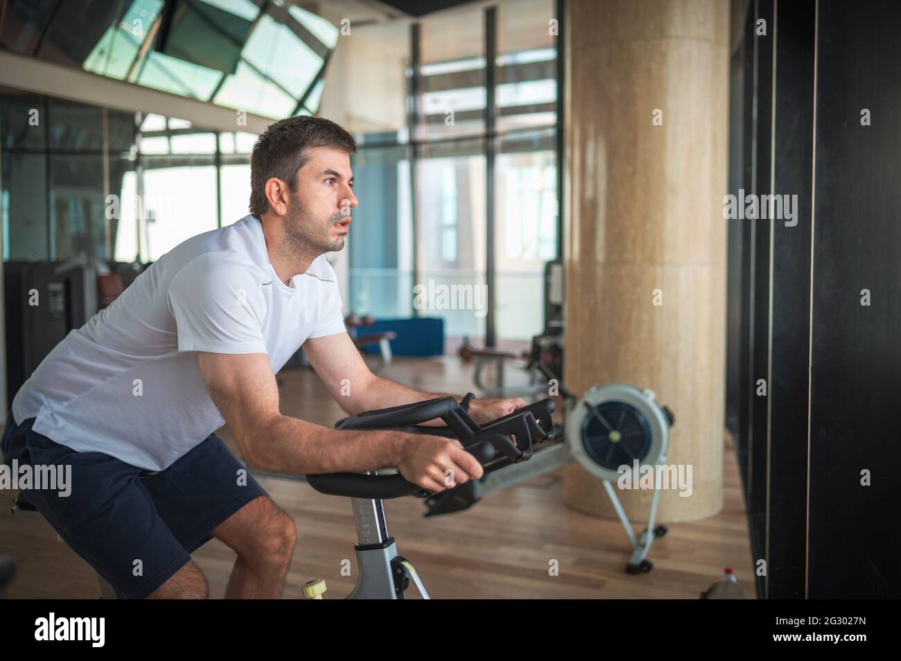 Kaukasischer Mann, der im Fitnessstudio trainiert und Heimtrainer in der Halle fährt. Gesunde Fitness Lifestyle abstrakt Stockfoto