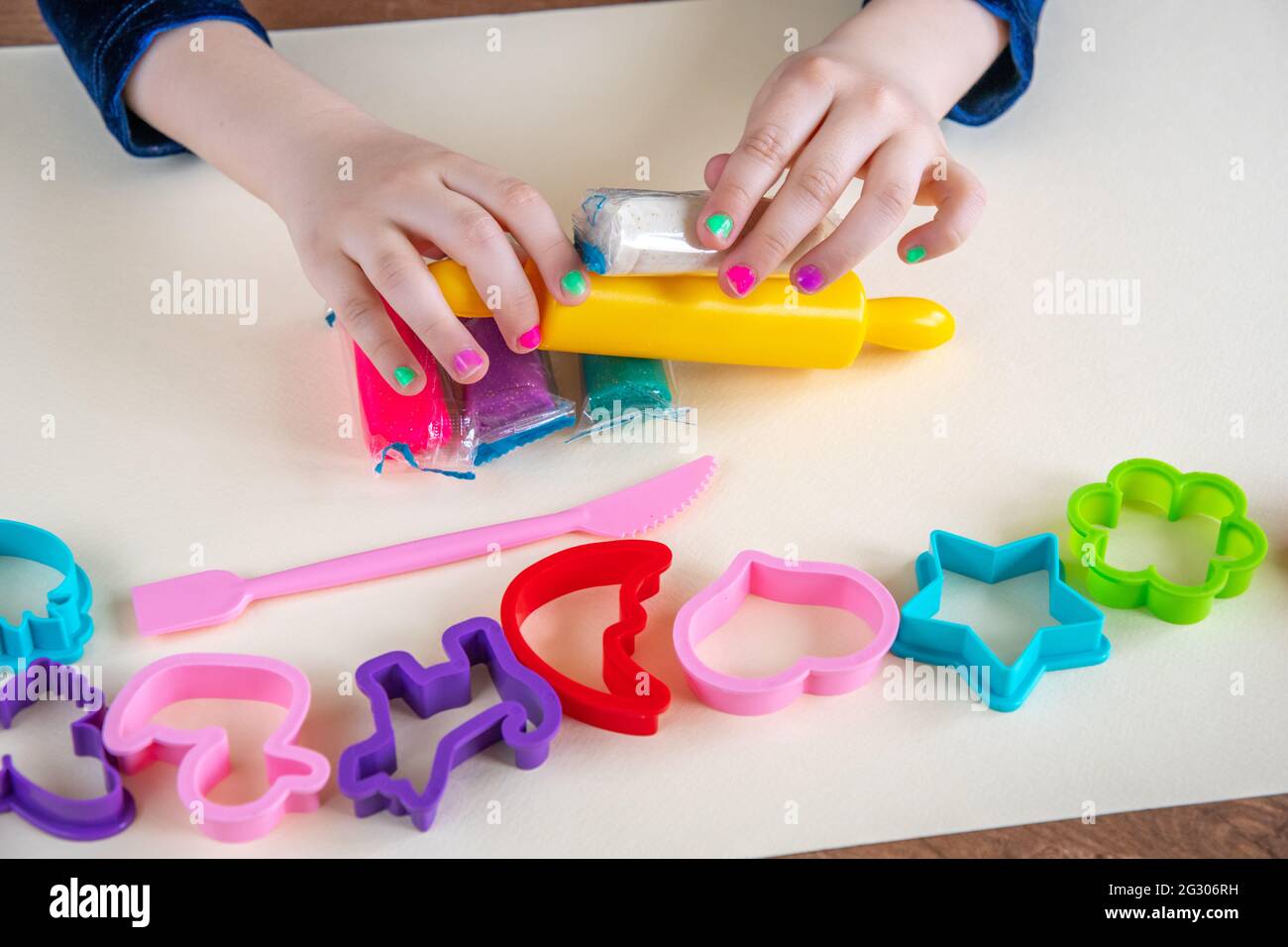 Mädchen Kleinkind spielt Plastilin oder spielen Ton von Fingern und mit kleinen gelben Nudelholz. Spiel Teig Form Set zur Verbesserung der Feinmotorik. Kind educ Stockfoto