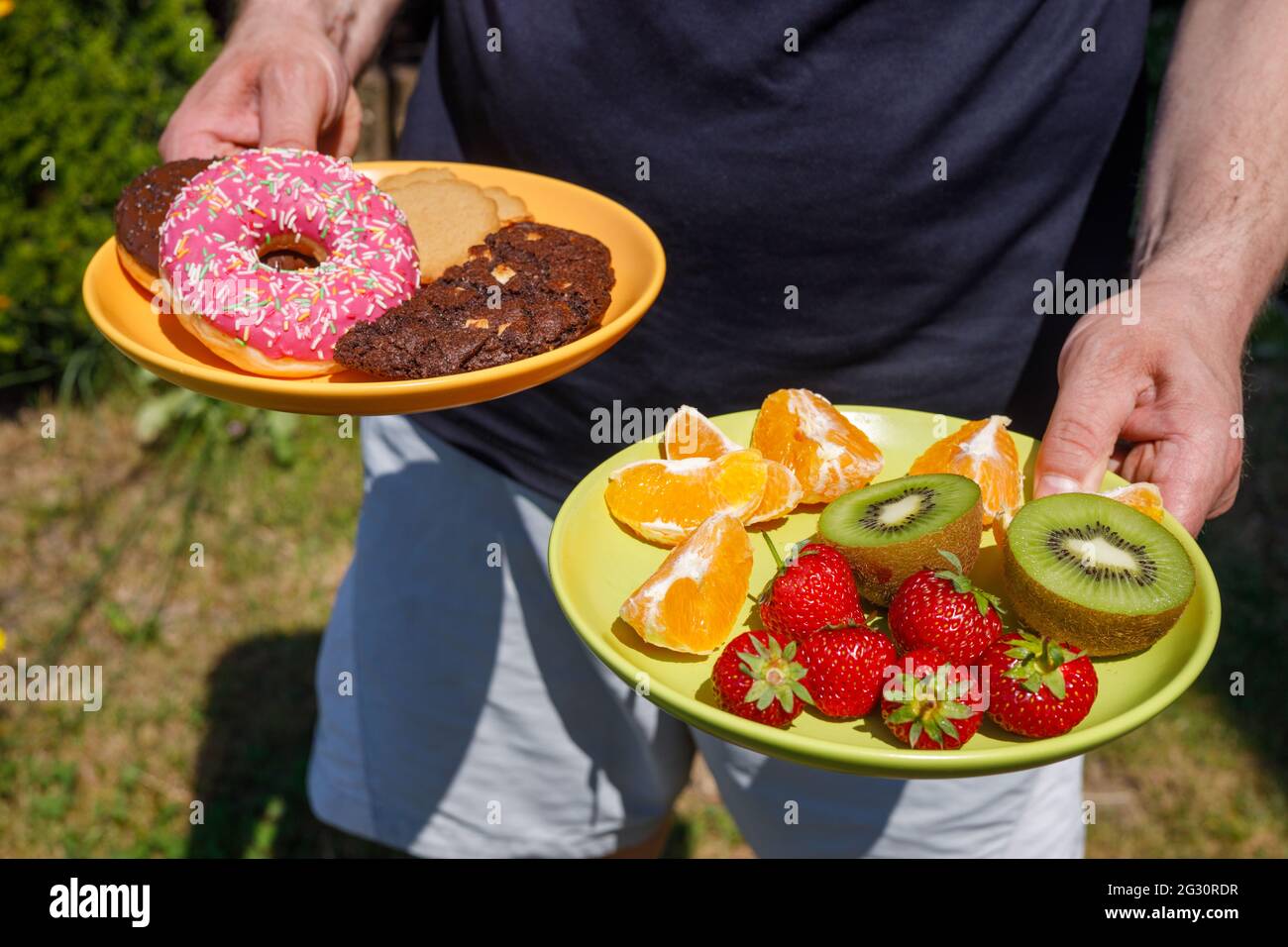 Gute Kalorien, der Mensch serviert eine Auswahl, Teller mit Cookies und Obst, gesund und ungesund, Ernährungskonzept Stockfoto
