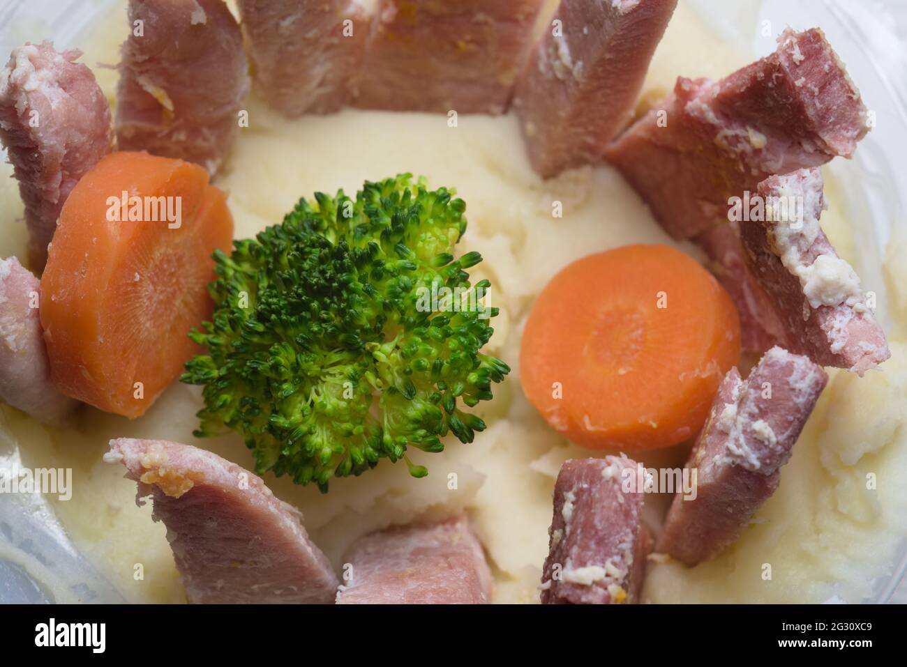 Blick auf ein einfaches und einfaches Abendessen. Bestehend aus Kartoffelbrei, Gammon, Brokkoli und Karotten. Alles in der Plastikwanne, die fertig gemacht wurde Stockfoto