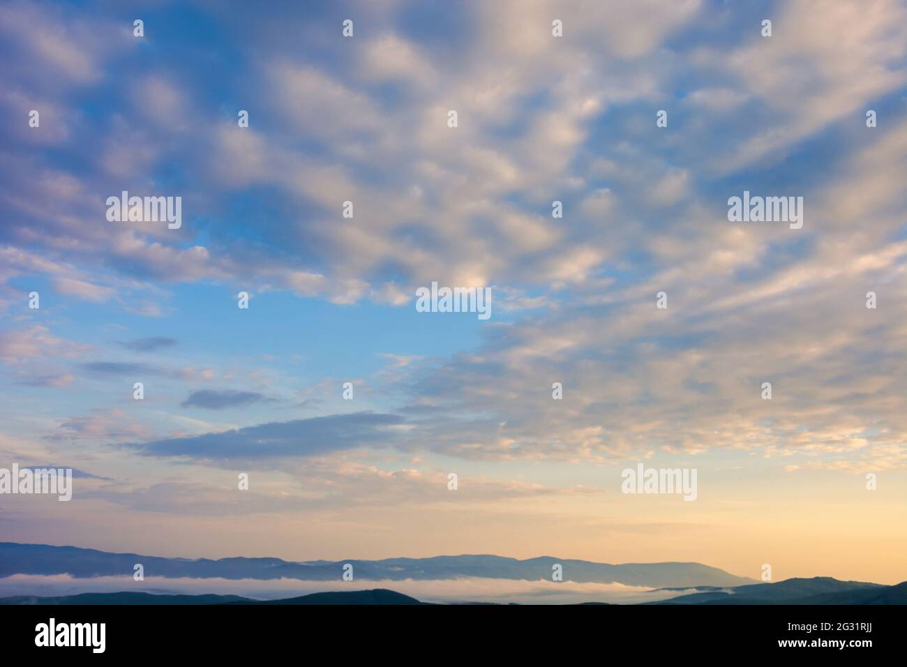 Flauschige Wolken am azurblauen Himmel bei Sonnenaufgang. Schöner Naturhintergrund. Panoramablick im goldenen Morgenlicht Stockfoto