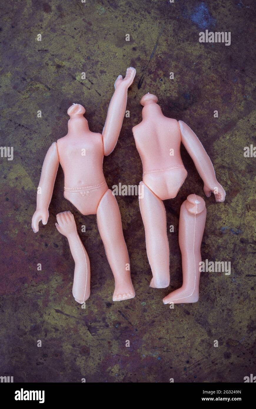 Zwei Körper moderner Plastikpuppen ohne Kopf und mit einigen Gliedmaßen, die auf angeschlättetem Messing liegen Stockfoto