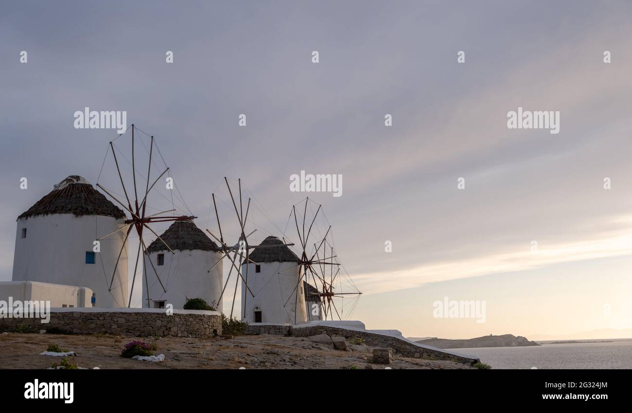 Traditionelle Windmühlen, Wahrzeichen der Insel Mykonos bei Sonnenaufgang, Kykladen Griechenland. Wolkiger Himmel im Hintergrund. Vorlage für die Sommerferien-Karte, Platz zum Kopieren Stockfoto