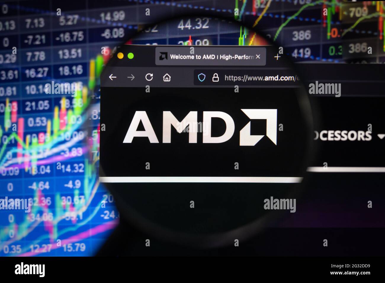 AMD-Firmenlogo auf einer Website mit verschwommenen Börsenentwicklungen im Hintergrund, auf einem Computerbildschirm durch eine Lupe gesehen Stockfoto