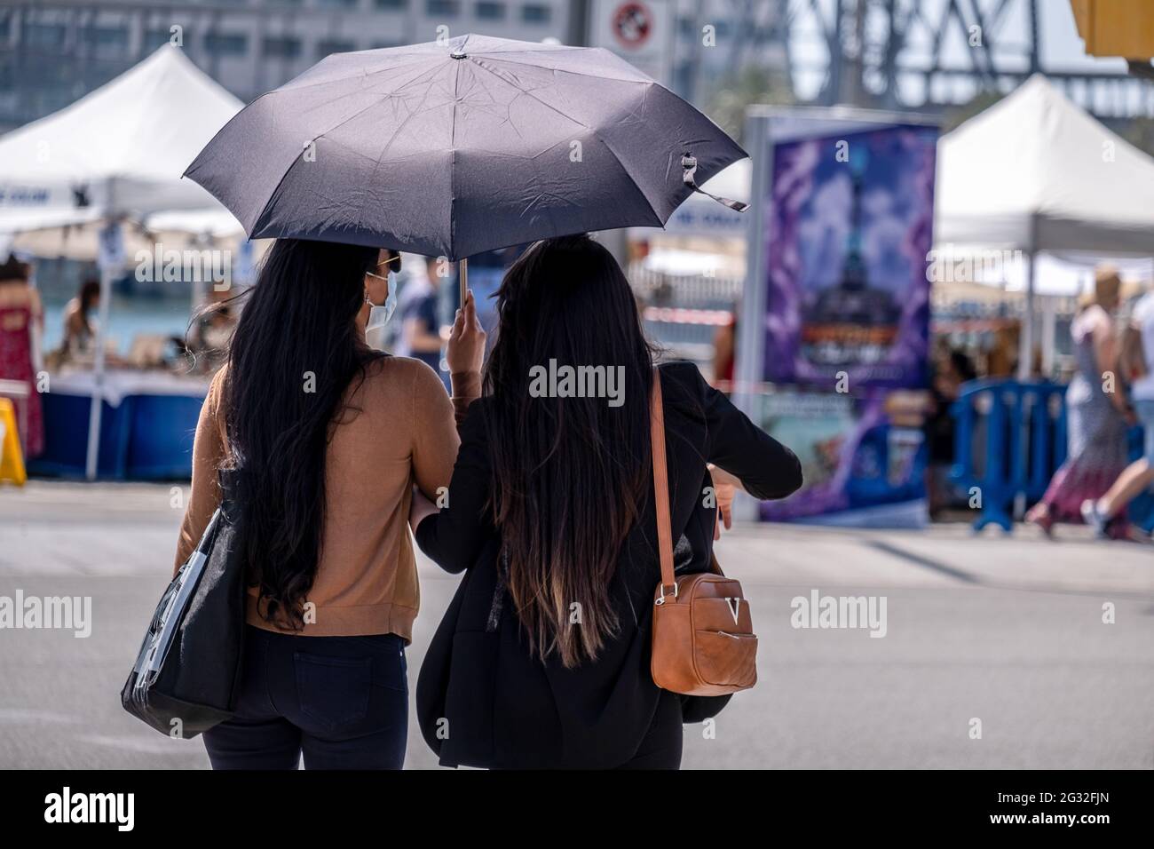 Barcelona, Spanien. Juni 2021. Touristen schützen sich vor der Sonne und hohen Temperaturen mit einem Regenschirm am Kolumbus-Denkmal in Barcelona.mit 50% der Bürger Kataloniens geimpft mit der ersten Dosis, beginnt der Tourismus in den Straßen von Barcelona zu sehen, vor allem in der Altstadt der Stadt. Bars, Geschäfte, Restaurants, Freizeitaktivitäten für den Tourismus, alle werden mit der Ankunft der Besucher aktiviert. Kredit: SOPA Images Limited/Alamy Live Nachrichten Stockfoto