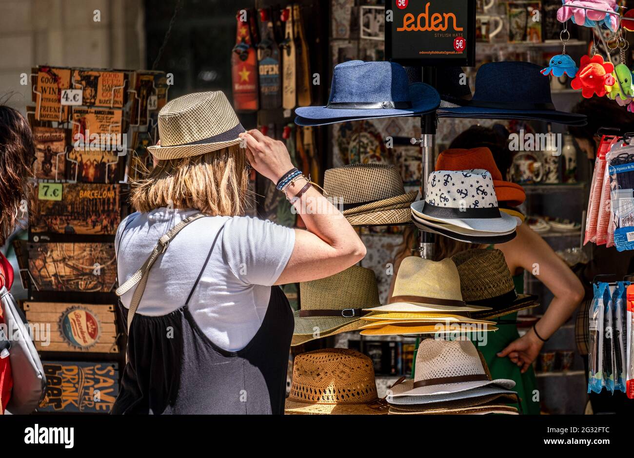Barcelona, Spanien. Juni 2021. Ein Tourist wird gesehen, wie er an einem Souvenir-Kiosk auf Las Ramblas Hüte probiert. Mit 50% der Bürger Kataloniens, die mit der ersten Dosis geimpft werden, beginnt der Tourismus in den Straßen von Barcelona zu sehen, vor allem im historischen Zentrum der Stadt. Bars, Geschäfte, Restaurants, Freizeitaktivitäten für den Tourismus, alle werden mit der Ankunft der Besucher aktiviert. Kredit: SOPA Images Limited/Alamy Live Nachrichten Stockfoto